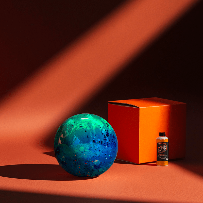 Hands holding a red orb with intricate, patterned artwork depicting a figure with sunglasses.