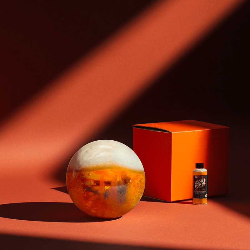 Hands holding a red orb with intricate, patterned artwork depicting a figure with sunglasses.