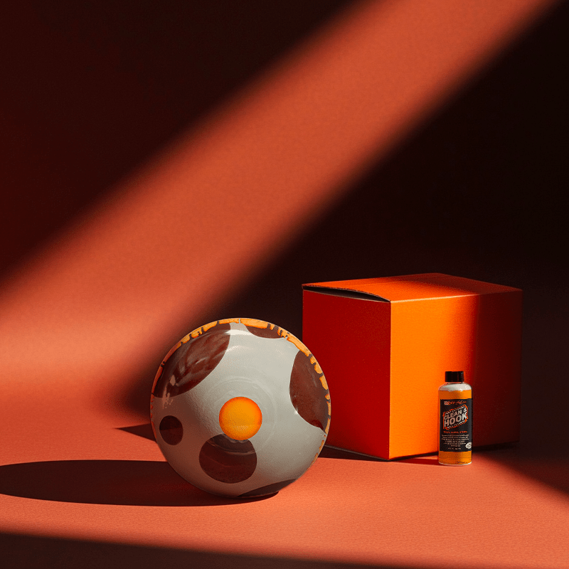 Hands holding a red orb with intricate, patterned artwork depicting a figure with sunglasses.