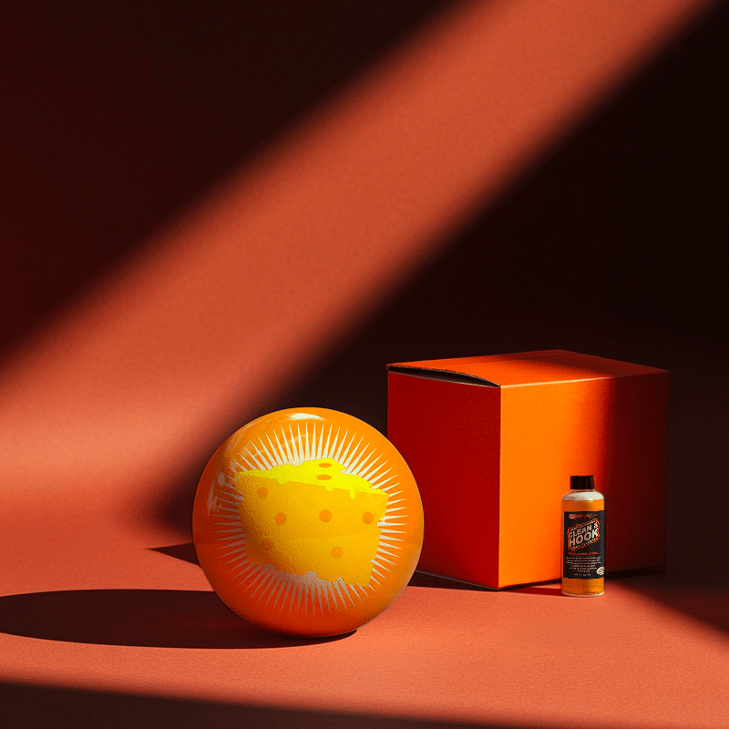 Hands holding a red orb with intricate, patterned artwork depicting a figure with sunglasses.