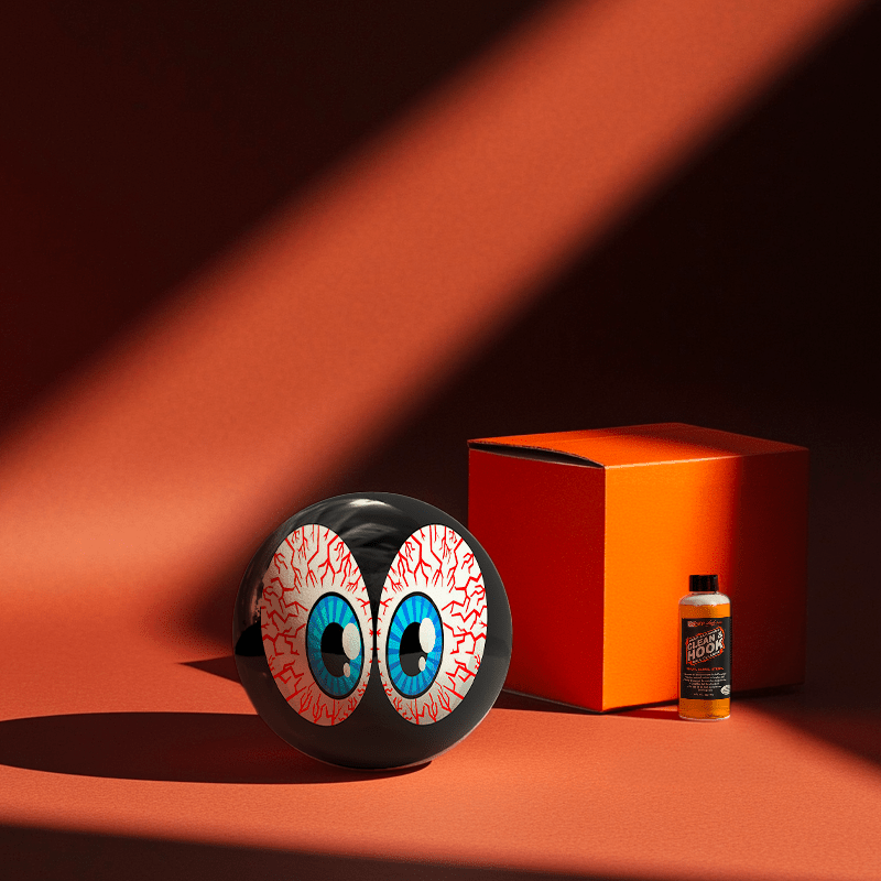 Hands holding a red orb with intricate, patterned artwork depicting a figure with sunglasses.