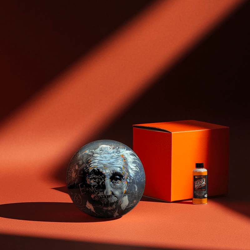 Hands holding a red orb with intricate, patterned artwork depicting a figure with sunglasses.