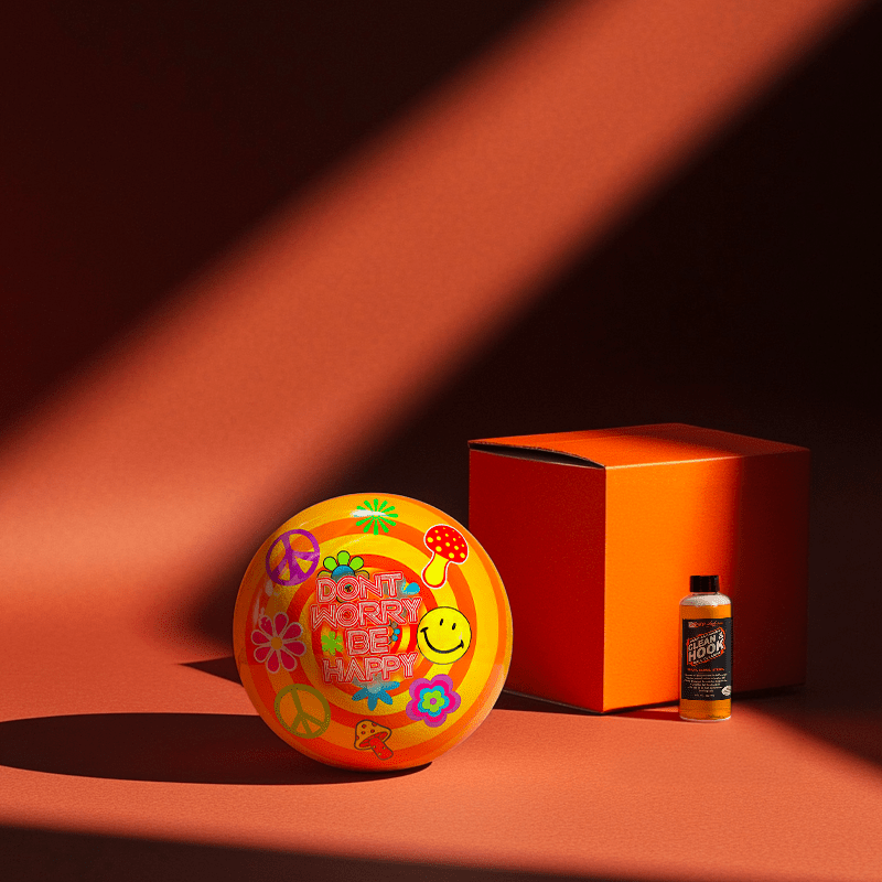 Hands holding a red orb with intricate, patterned artwork depicting a figure with sunglasses.