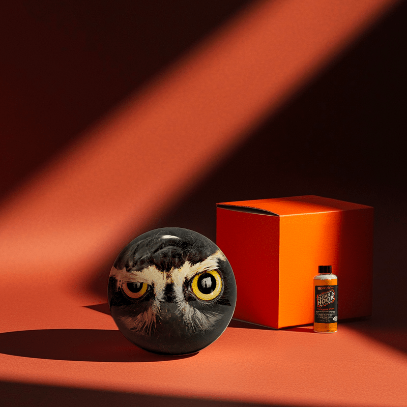 Hands holding a red orb with intricate, patterned artwork depicting a figure with sunglasses.