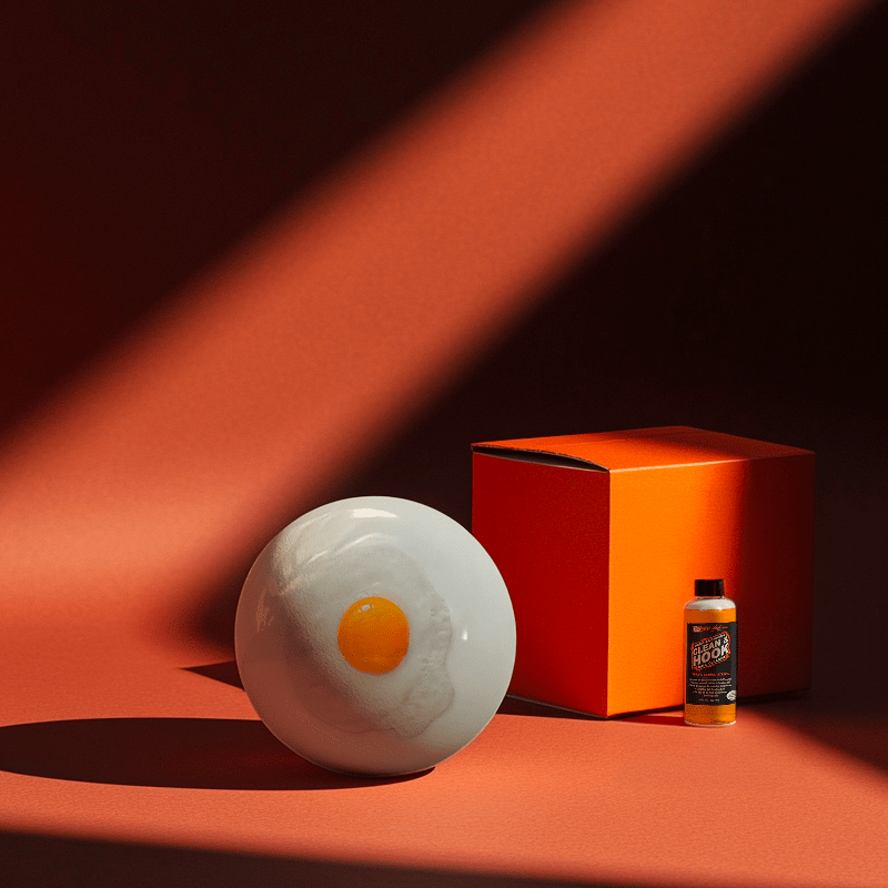 Hands holding a red orb with intricate, patterned artwork depicting a figure with sunglasses.