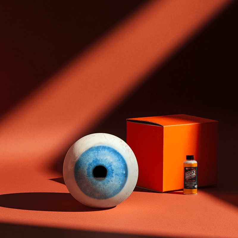 Hands holding a red orb with intricate, patterned artwork depicting a figure with sunglasses.