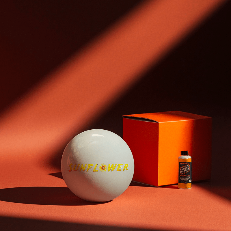 Hands holding a red orb with intricate, patterned artwork depicting a figure with sunglasses.