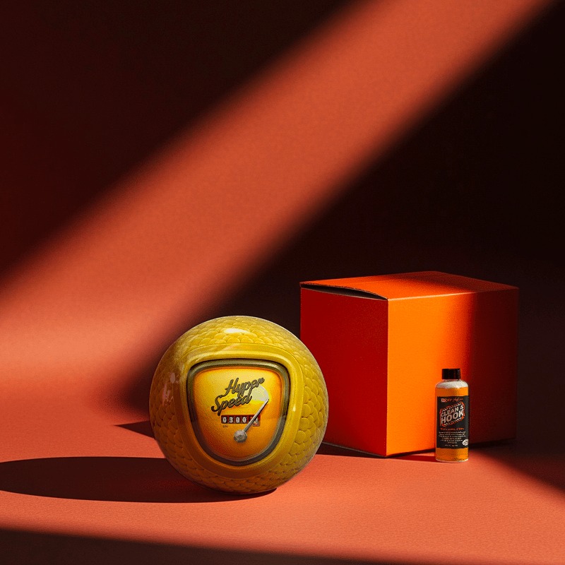 Hands holding a red orb with intricate, patterned artwork depicting a figure with sunglasses.