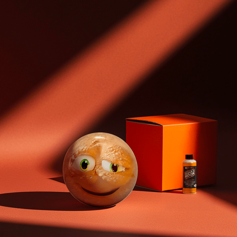 Hands holding a red orb with intricate, patterned artwork depicting a figure with sunglasses.