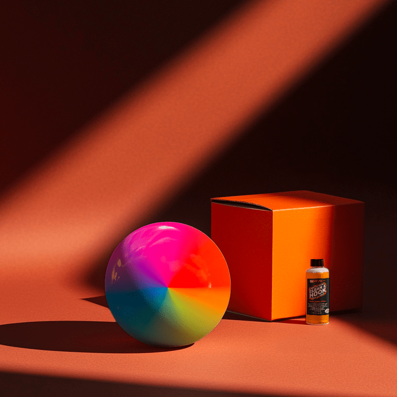 Hands holding a red orb with intricate, patterned artwork depicting a figure with sunglasses.