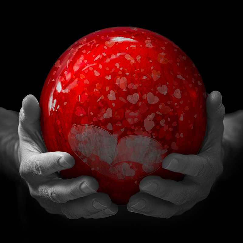 Hands holding a red sphere featuring a floral-patterned figure.