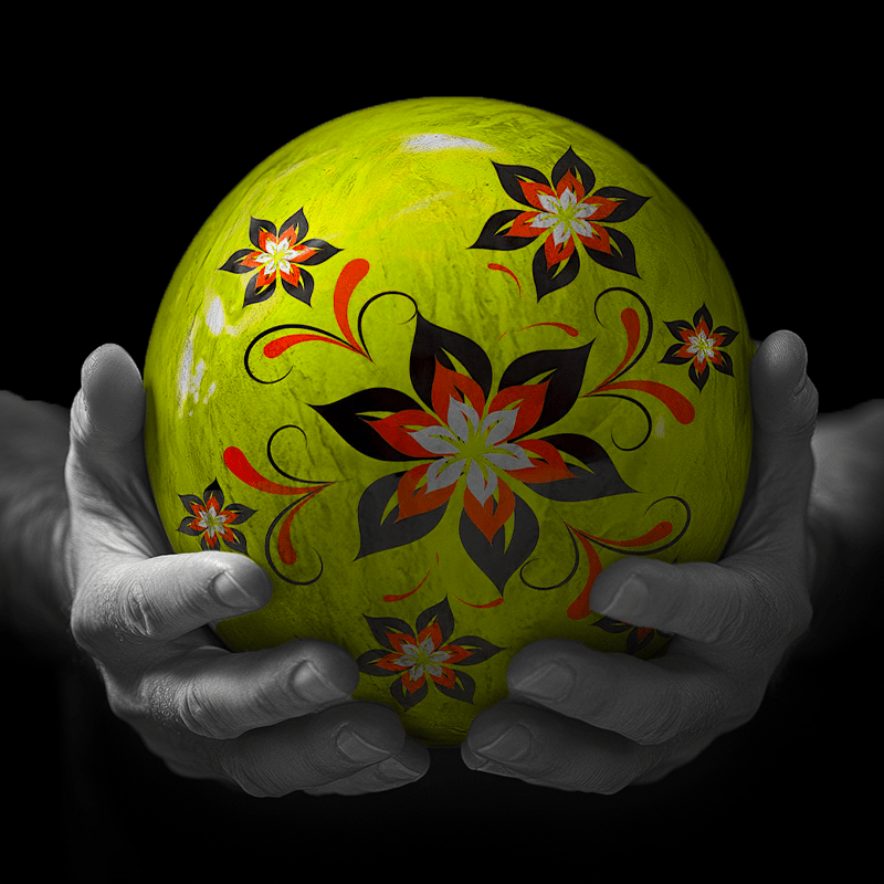 Hands holding a red sphere featuring a floral-patterned figure.