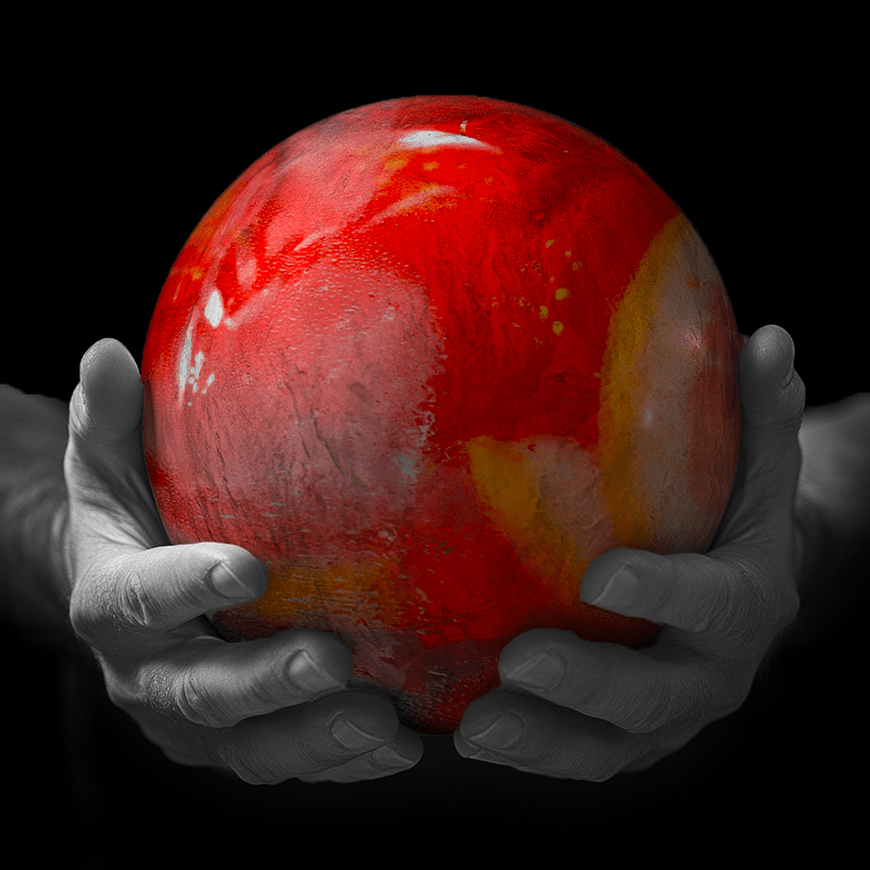 Hands holding a red sphere featuring a floral-patterned figure.