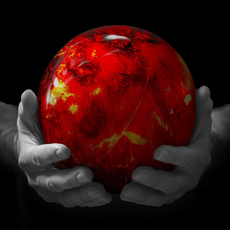 Hands holding a red sphere featuring a floral-patterned figure.