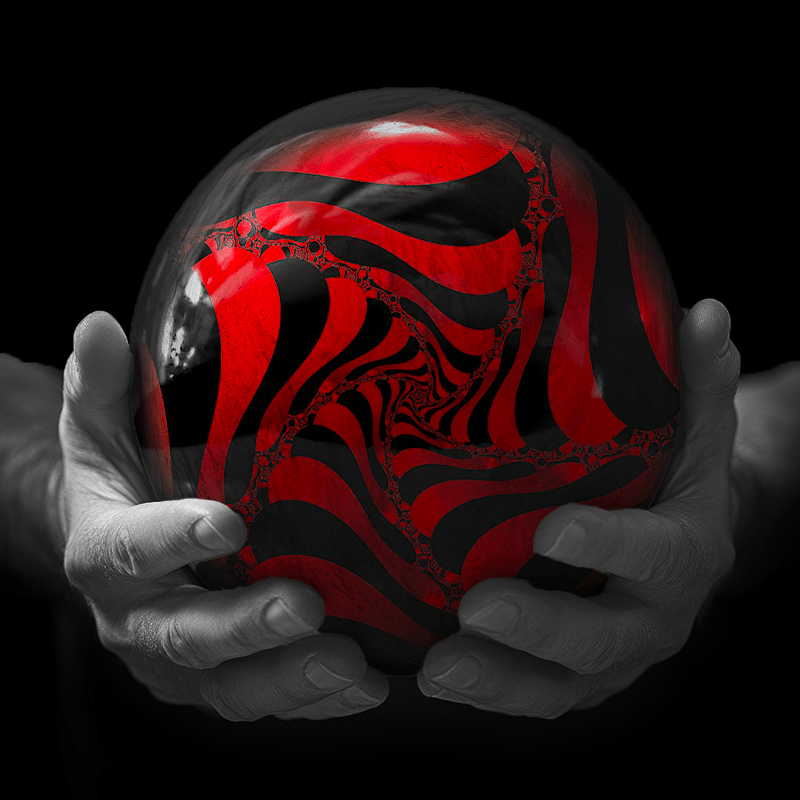 Hands holding a red sphere featuring a floral-patterned figure.