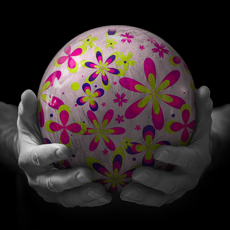 Hands holding a red sphere featuring a floral-patterned figure.