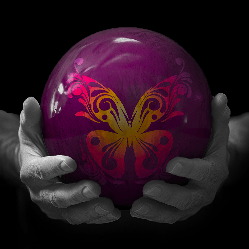 Hands holding a red sphere featuring a floral-patterned figure.